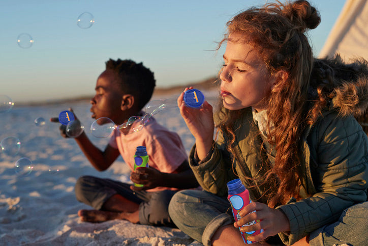 Children blowing eco-friendly bubbles using their refillable aluminum bottles